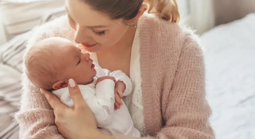 Delikatna pozycja do odbijania noworodka w ramionach mamy, która tuli go z miłością.