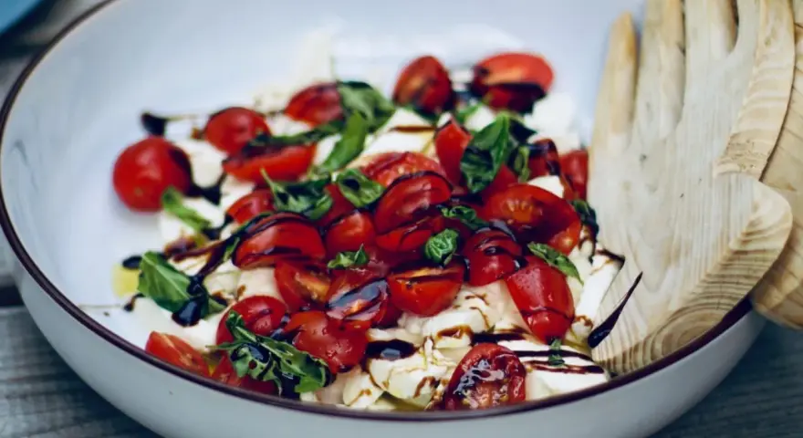 Frische Insalata Caprese mit saftigen Tomaten, cremigem Mozzarella und Basilikum, beträufelt mit Balsamico.