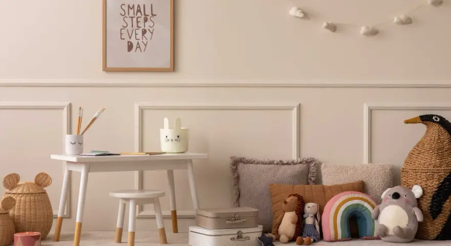 Ein Kinderzimmer mit einem kleinen Schreibtisch, Spielzeug und einem Bild mit der Aufschrift "Small steps every day". Eine beige Mom würde sich hier wohlfühlen.