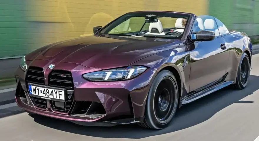 Fioletowe sportowe auta BMW M4 kabriolet pędzi po drodze.