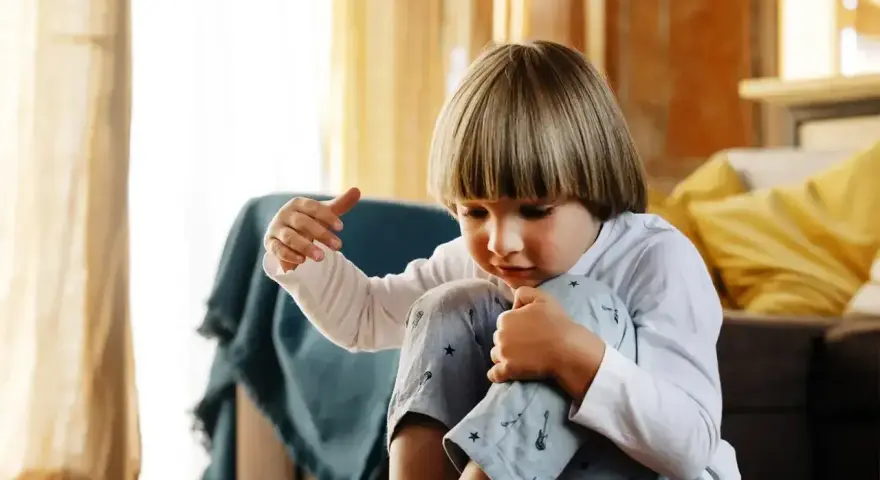 Chłopiec zamyślony, przytula kolana. Czy to może być co to jest tik?