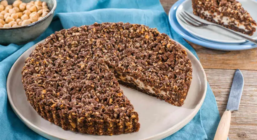 Sbriciolata ricotta e cioccolato con croccante copertura di nocciole. Una fetta invitante attende su un piattino.