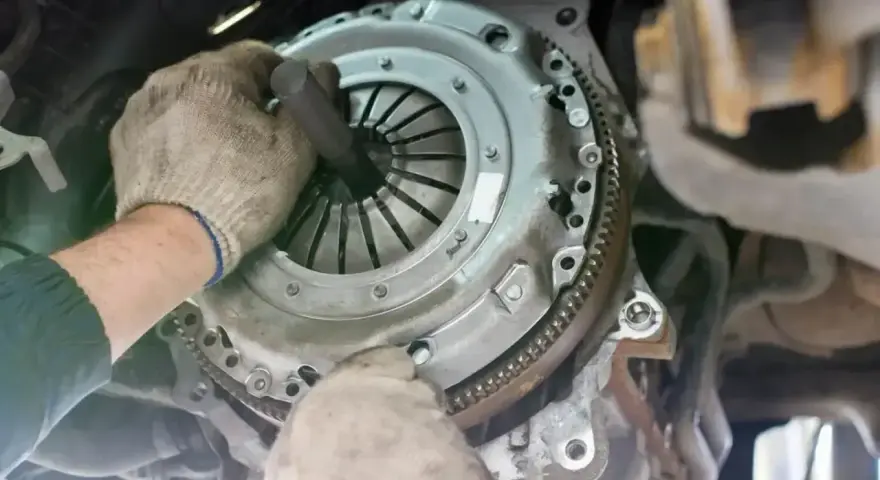 Mechanik w rękawiczkach montuje tarczę sprzęgła, przygotowując wysprzęglik sprzęgła do pracy.