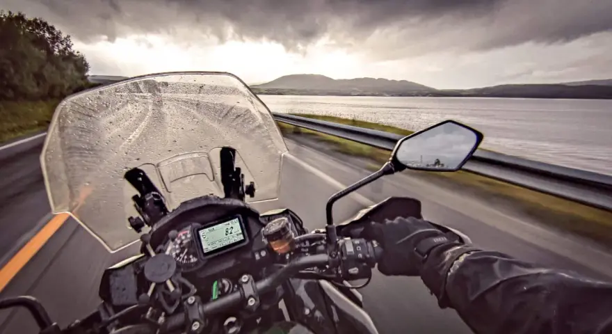 Jazda motocyklem w deszczu w kierunku Nordkapp. Pochmurne niebo i mokra droga nie zniechęcają do podróży.