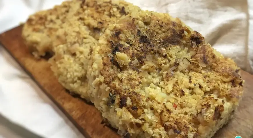 Dos hamburguesas doradas de mijo sobre tabla de madera.