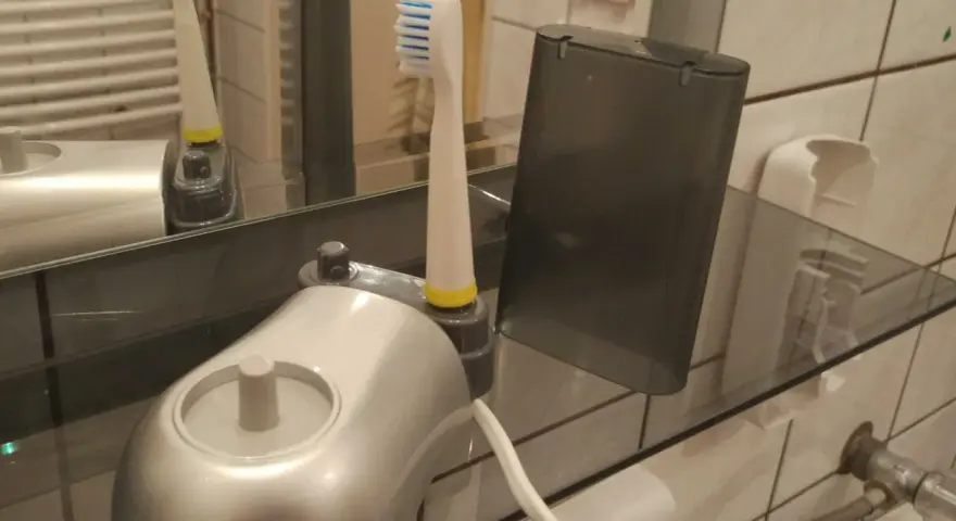 Pierwsze ładowanie szczoteczki elektrycznej. Nowa szczoteczka z ładowarką i etui na półce w łazience.