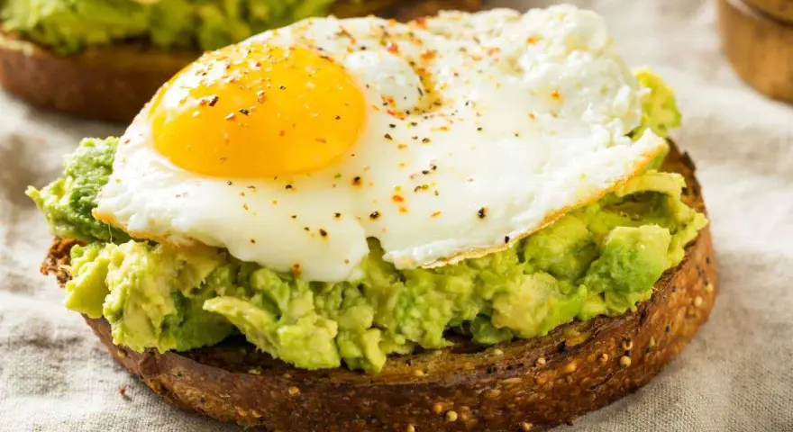 Tostada integral con aguacate machacado y huevo frito, un delicioso desayuno keto.
