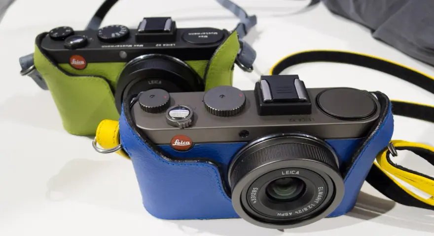 Dwie stylowe Leica X2 w kolorowych futerałach: jedna zielona, druga niebieska. Idealne do uchwycenia każdej chwili.