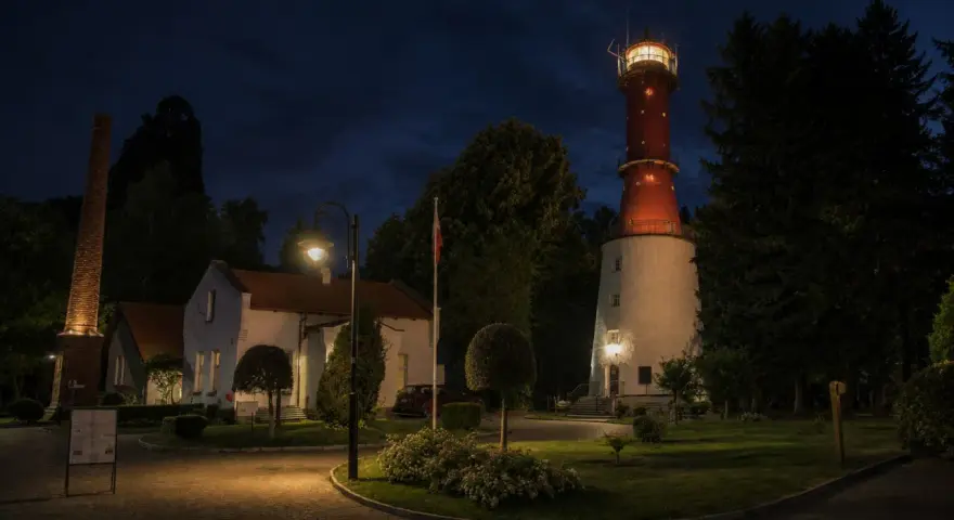 Nocna panorama latarni morskiej Rozewie z oświetloną wieżą i budynkami.