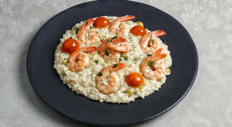 Kremowe risotto z krewetkami i pomidorkami koktajlowymi, posypane natką pietruszki. Idealny przepis na risotto dla każdego.