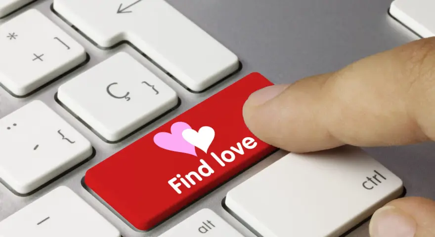 Palec naciska czerwony klawisz z sercami i napisem "Find love", symbolizując bezpieczne randki online.