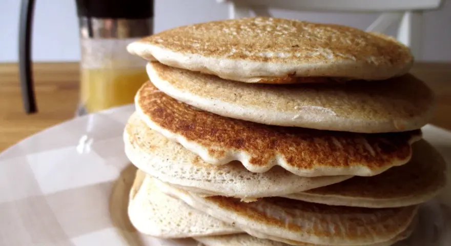 Pila di soffici pancake con farina di avena, dorati e invitanti, pronti per una colazione sana e gustosa.