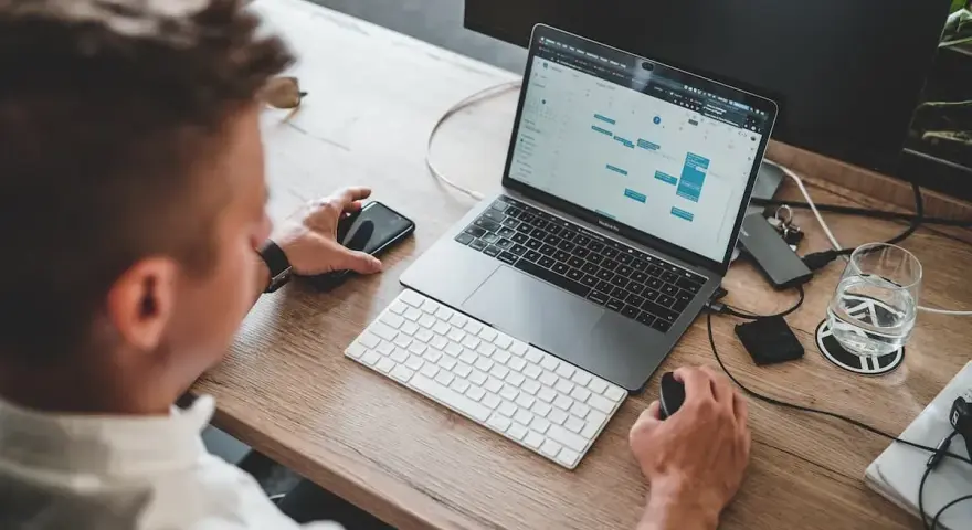 Mężczyzna pracuje przy laptopie, planując zadania. To idealne miejsce do nauki, by rozpocząć kurs spedytora i zdobyć nowe umiejętności.