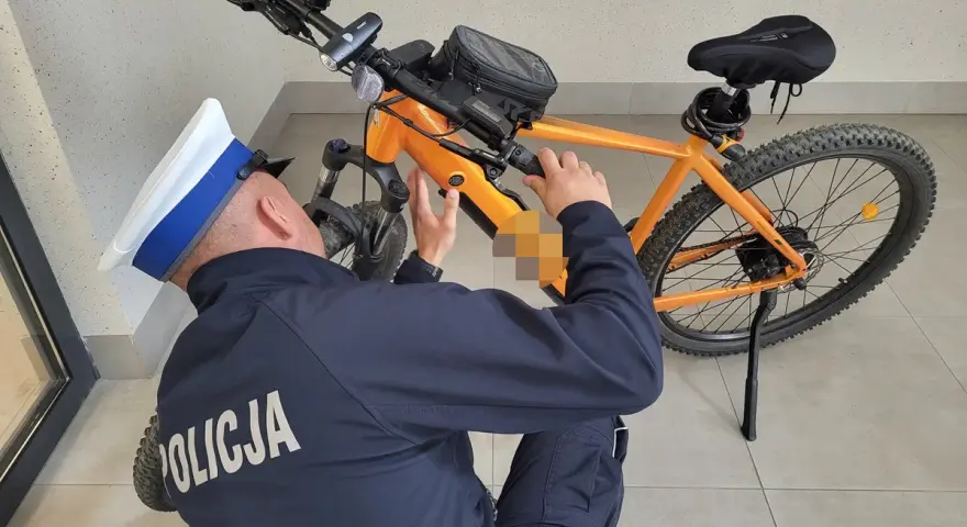 Policjant sprawdza, czy na rower elektryczny trzeba mieć prawo jazdy. Pomarańczowy rower z silnikiem.