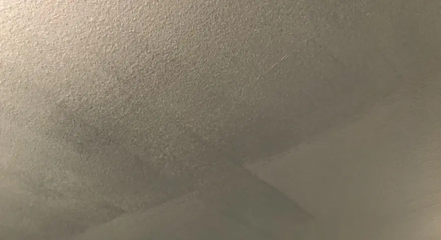 Ett flammigt tak efter målning, med synliga penseldrag och en textur som påminner om sand.