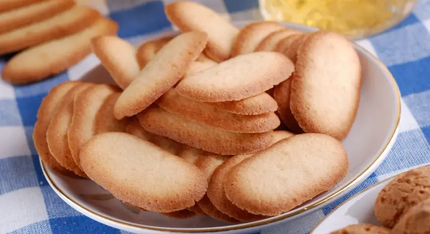 Un piatto pieno di croccanti lingue di gatto, perfette per accompagnare un tè o un caffè.