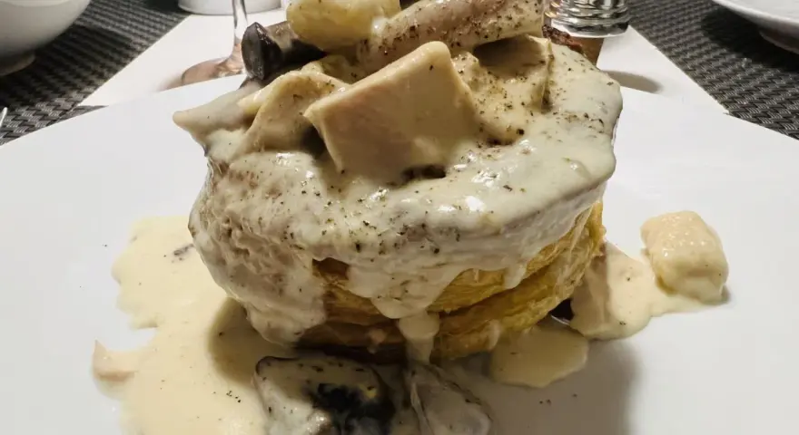 Une bouchée à la reine rapide, garnie de poulet, champignons et d'une sauce crémeuse, servie sur une pâte feuilletée dorée.