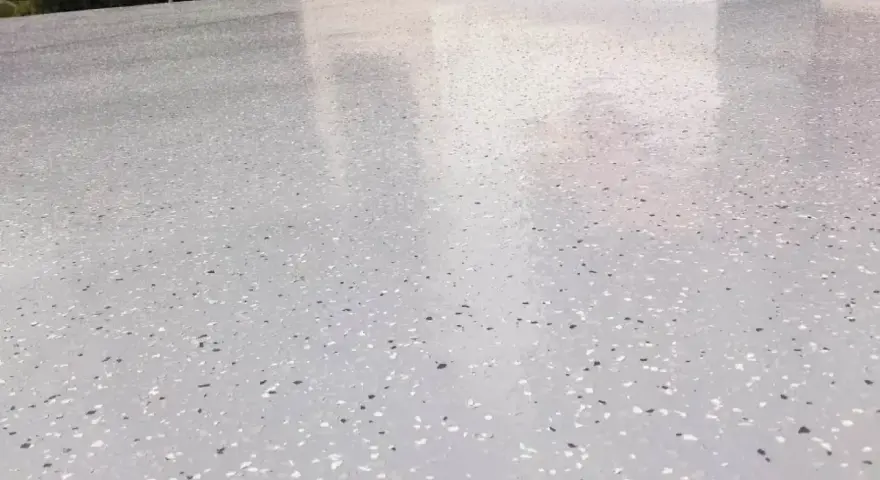 Nowoczesny kamienny dywan koszt 1m2. Jasnoszara powierzchnia z drobnymi, kolorowymi płatkami, idealna na taras.