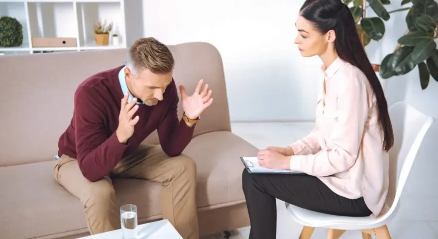 Mężczyzna rozmawia z psychologiem, siedząc na kanapie.