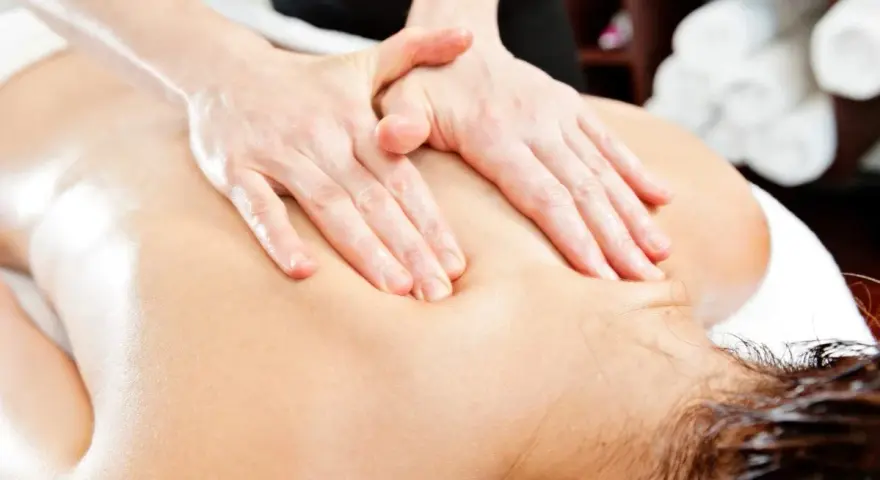 Hands perform a relaxing massage on a person's back, evoking the gentle pressure of shiatsu massage vs deep tissue.