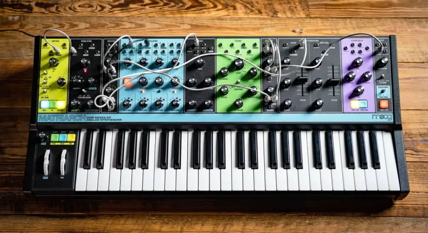 Moog Matriarch, półmodularny syntezator analogowy, z klawiaturą i licznymi pokrętłami i złączami, gotowy do tworzenia dźwięków.