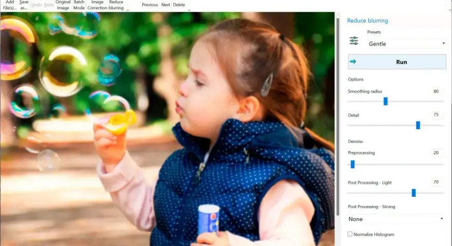 Dziewczynka dmucha bańki. Program Easy Photo Unblur pomaga jak wyostrzyć zdjęcie, oferując opcje redukcji rozmycia i poprawy detali.