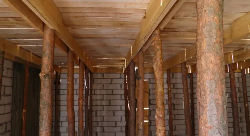 Szalowanie stropu z drewnianymi stemplami, tworzącymi rusztowanie pod przyszły strop.