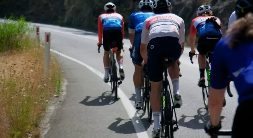 Cyclists in racing gear tackle a steep road, their shadows stretching long on the asphalt. This is the essence of category climbs cycling.