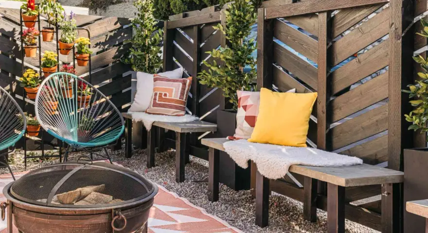 A cozy patio with a diy privacy screen, fire pit, and colorful chairs.