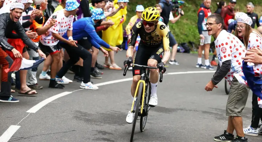 Jonas Vingegaard, with his impressive VO2 max, powers through a crowd of cheering fans in a cycling race.
