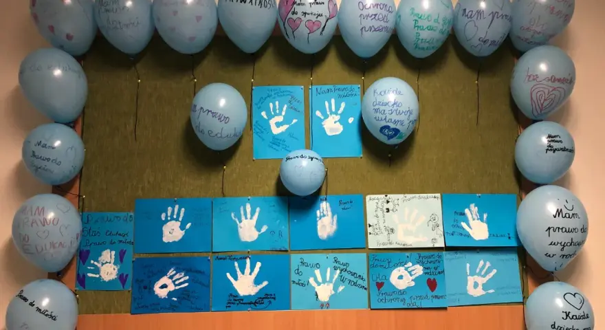 Dzień dziecka w szkole: niebieskie balony z napisami o prawach dzieci i rysunki dłoni.