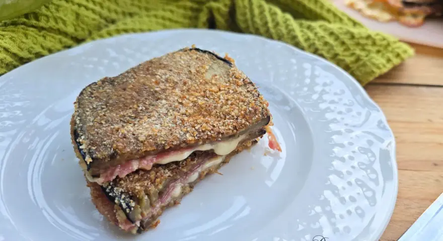 Un goloso cordon bleu di melanzane, impanato e fritto, con un cuore filante di formaggio e prosciutto.
