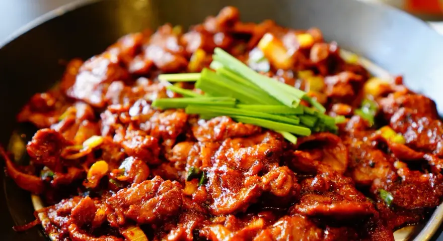 Pyszne wieprzowina po koreańsku w pikantnym sosie, udekorowana zieloną cebulką.