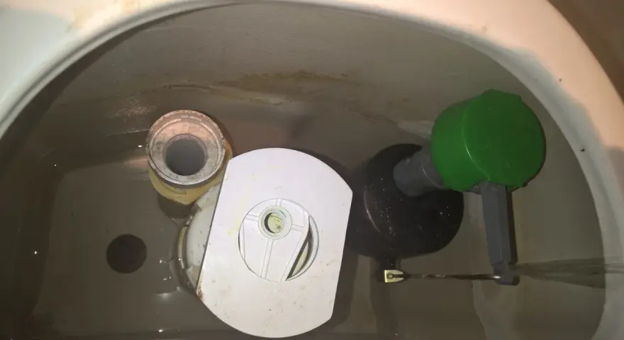 Insidan av en toalettcistern med en Gustavsberg Nordic 2002-mekanism. Vatten rinner ner från flottören.