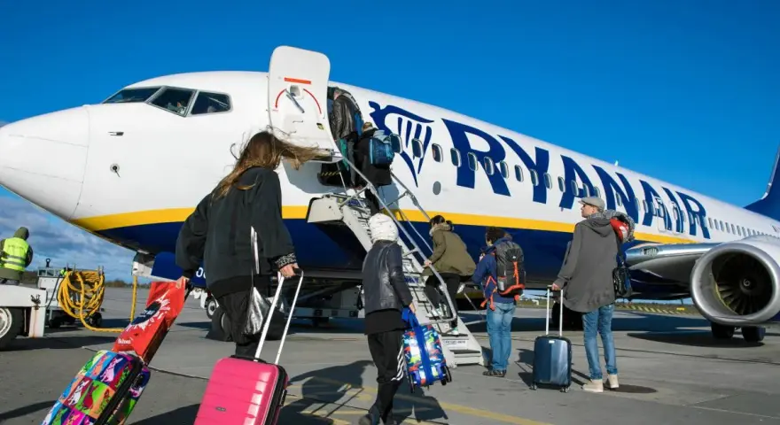 Ludzie z bagażami wsiadają do samolotu Ryanair. Może to być początek podróży lub sytuacja, gdy ktoś planuje **Ryanair zwrot biletu**.