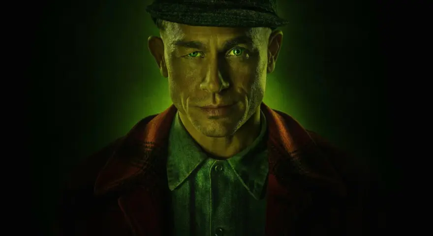 Mężczyzna z zielonymi oczami i czapką na głowie, w tle zielona poświata. Zapowiada mroczne seriale kryminalne Netflix.