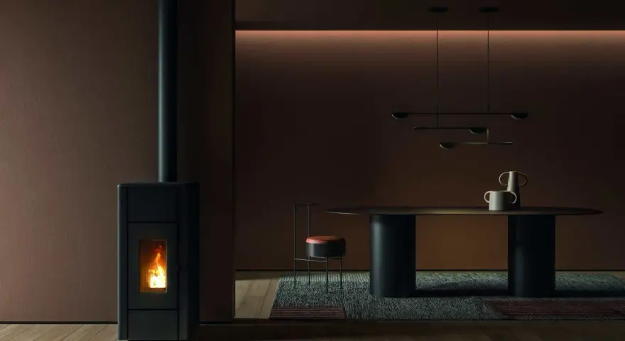 Un poêle à granulés dégage une douce chaleur, la flamme danse dans la chambre de combustion. La température ambiante est agréable, la fumée s'échappe par la cheminée.