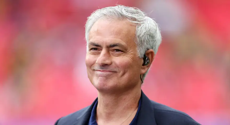 Uśmiechnięty José Mourinho, były trener Realu Madryt, z siwymi włosami i słuchawką w uchu.