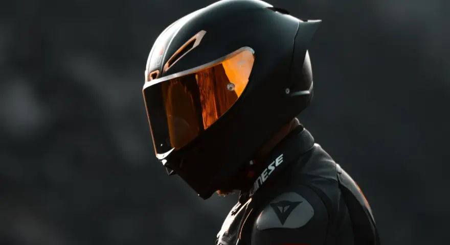 Casco nero lucido con visiera arancione riflettente, pronto per un giro in moto.