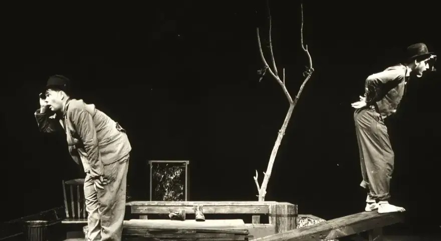 Dwóch mężczyzn w kapeluszach na scenie, w surrealistycznej scenografii. Scena z eugène ionesco sztuki, pełna absurdu i niepokoju.