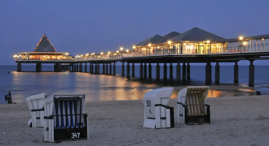 Strandkörbe am Abend vor der beleuchteten Seebrücke in Heringsdorf. Ein perfekter Ort für Geheimtipps am Meer.