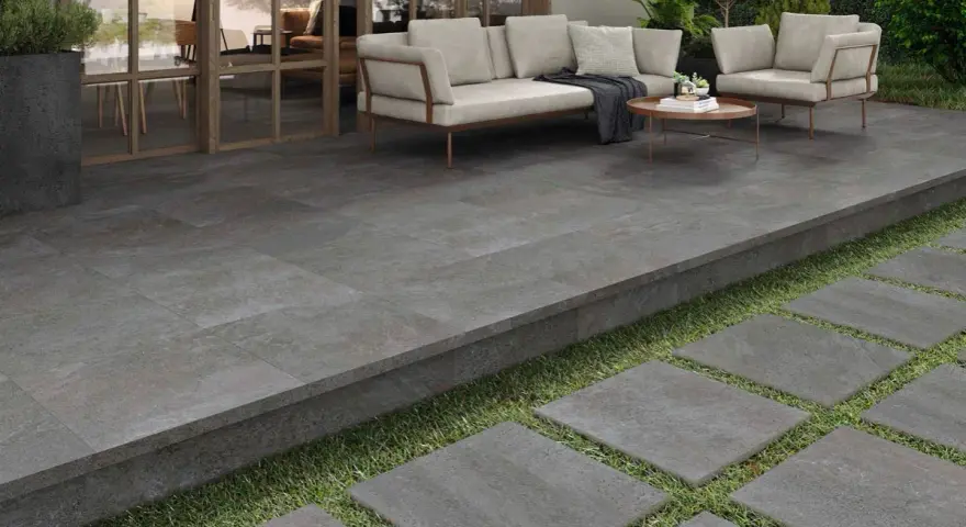 Terraza moderna con suelo de baldosas grises, ideal para saber como poner baldosas en suelo de tierra. Sofá y sillones invitan al descanso.