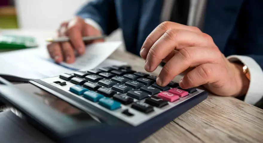 Man con traje calculando en calculadora. Los suplidos llevan IVA, un detalle importante en la contabilidad.