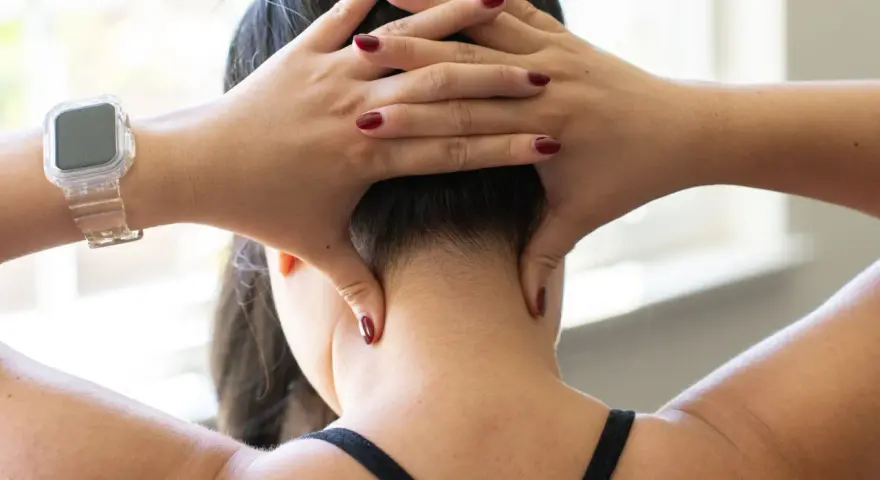 Hands demonstrate shiatsu self neck massage techniques, applying pressure to the base of the skull and sides of the neck.