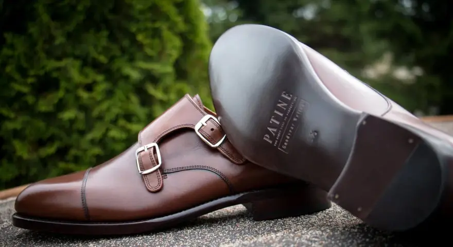 Eleganckie brązowe buty z podwójnymi klamrami, wykonane z wysokiej jakości kruponu. Widoczna podeszwa z logo marki.