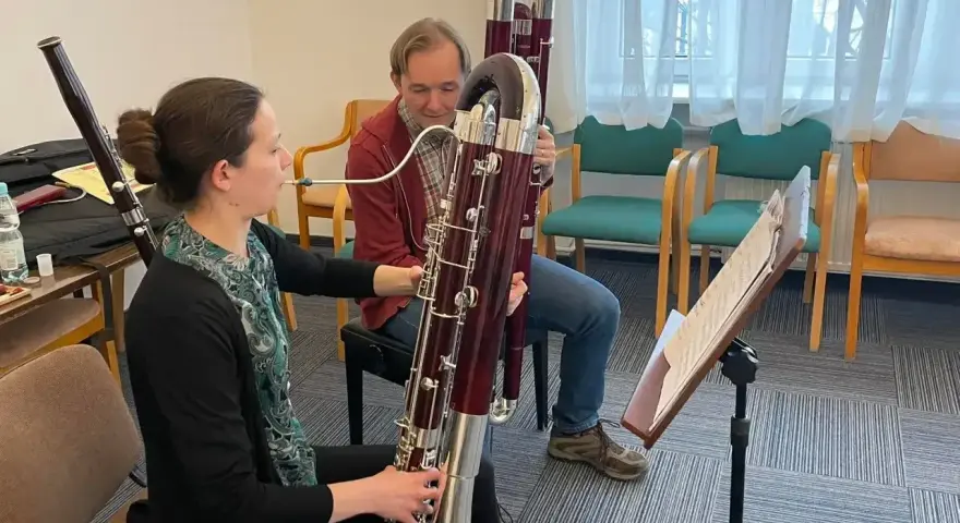 Kobieta i mężczyzna ćwiczą grę na fagotach. Jaki to instrument? Dwa duże, drewniane instrumenty dęte drewniane, fagot, są w centrum uwagi.