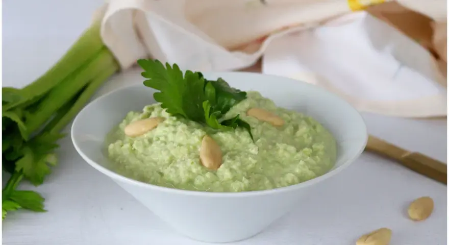 Pesto di sedano fresco, guarnito con mandorle e prezzemolo, pronto per essere gustato.