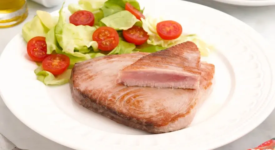 Delicioso atún a la plancha con ensalada fresca de lechuga y tomates cherry. Un plato ligero y saludable.