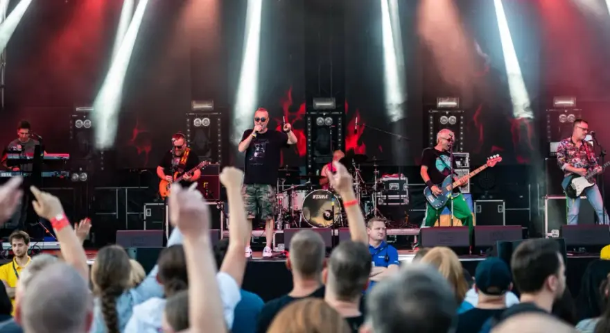 Zespół gra na scenie podczas festiwalu w Jarocinie. Widać publiczność, światła i instrumenty.
