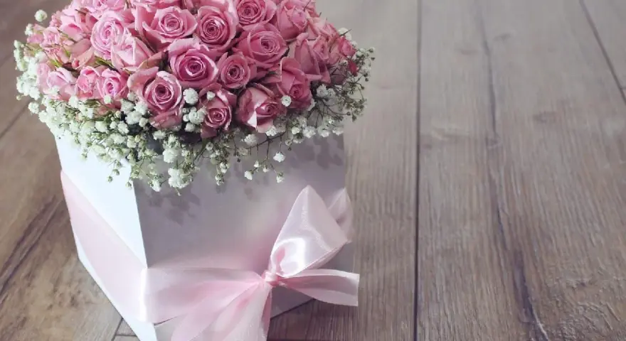 Piękne różowe róże w białym pudełku z różową wstążką. Idealne na prezent, pokazują, jak zrobić pudełko do flower box.